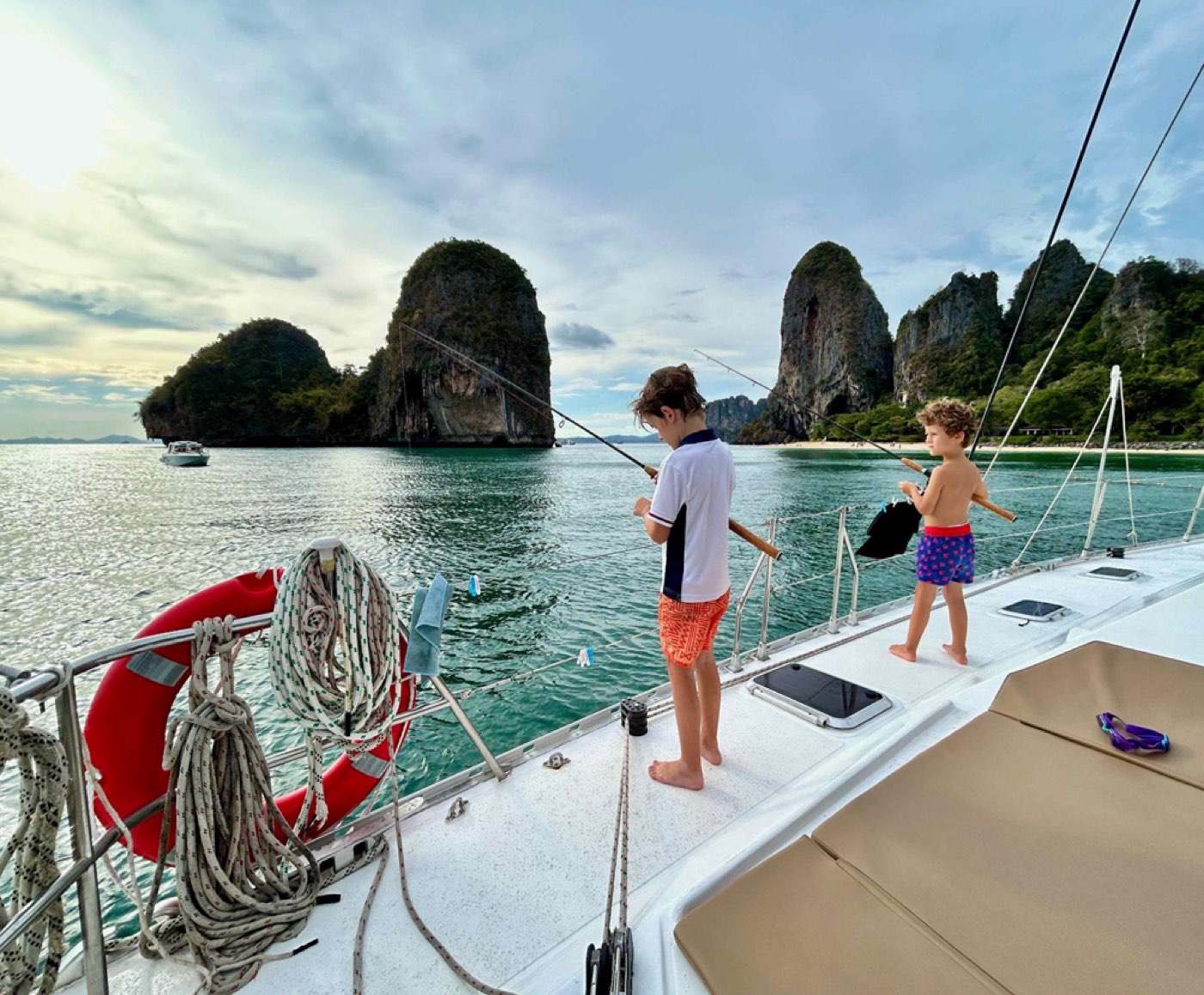 Enfants pêchant depuis le pont d'un catamaran face aux falaises de Railay