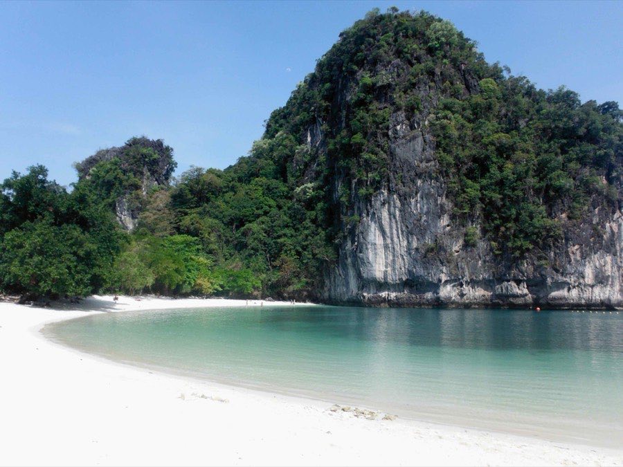 Plage de sable blanc au pied d'une île calcaire